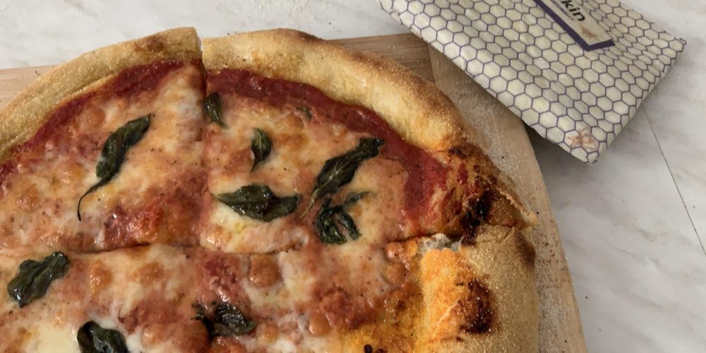photo showing cooked Neapolitan pizza alongside beeskin beeswax wrap size L used in proofing the dough
