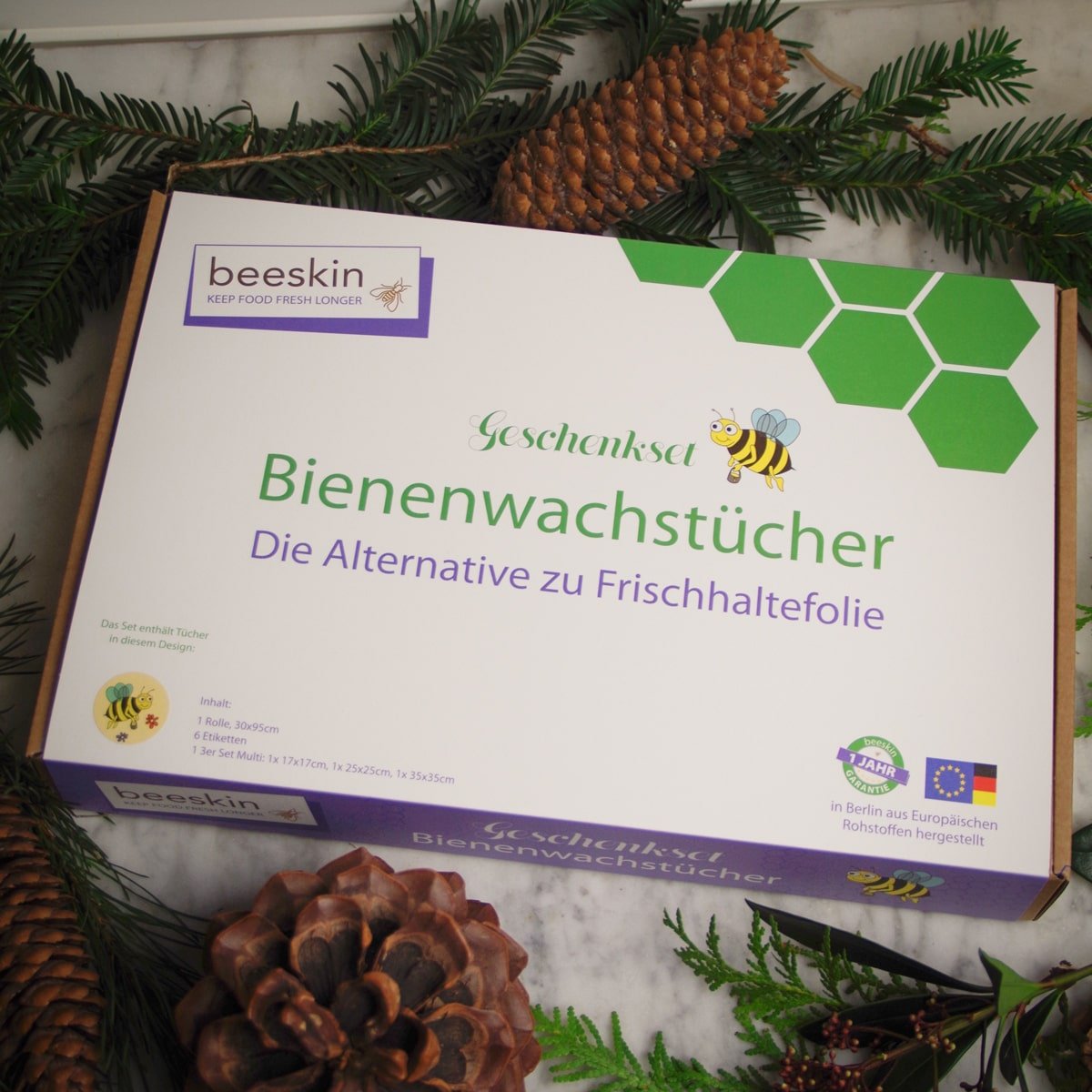 beeskin beeswax giftbox packaging lies on a table surrounded by pine and pine cones