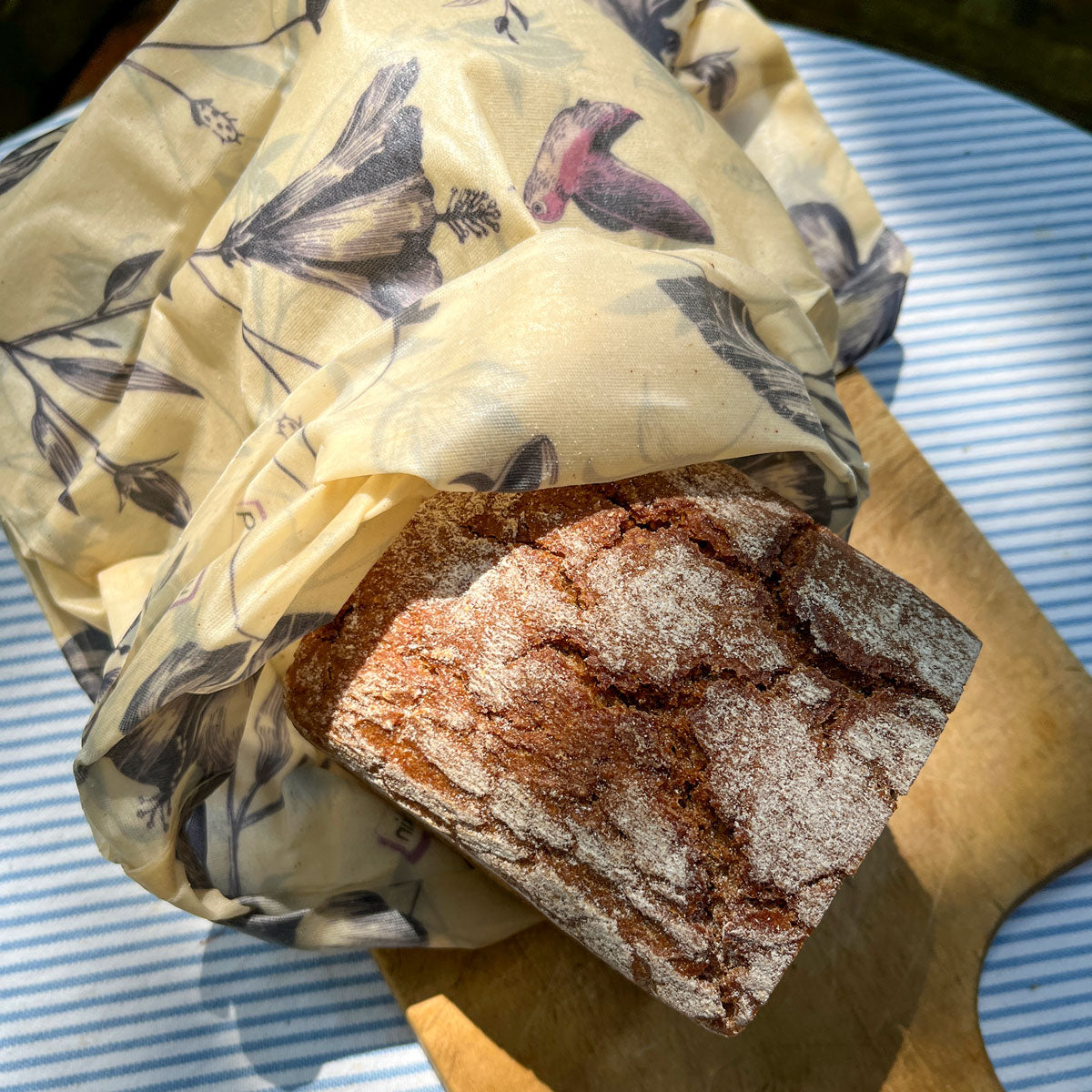 half a loaf of bread in a rolled up beeswax bag hummingbird on a wooden board