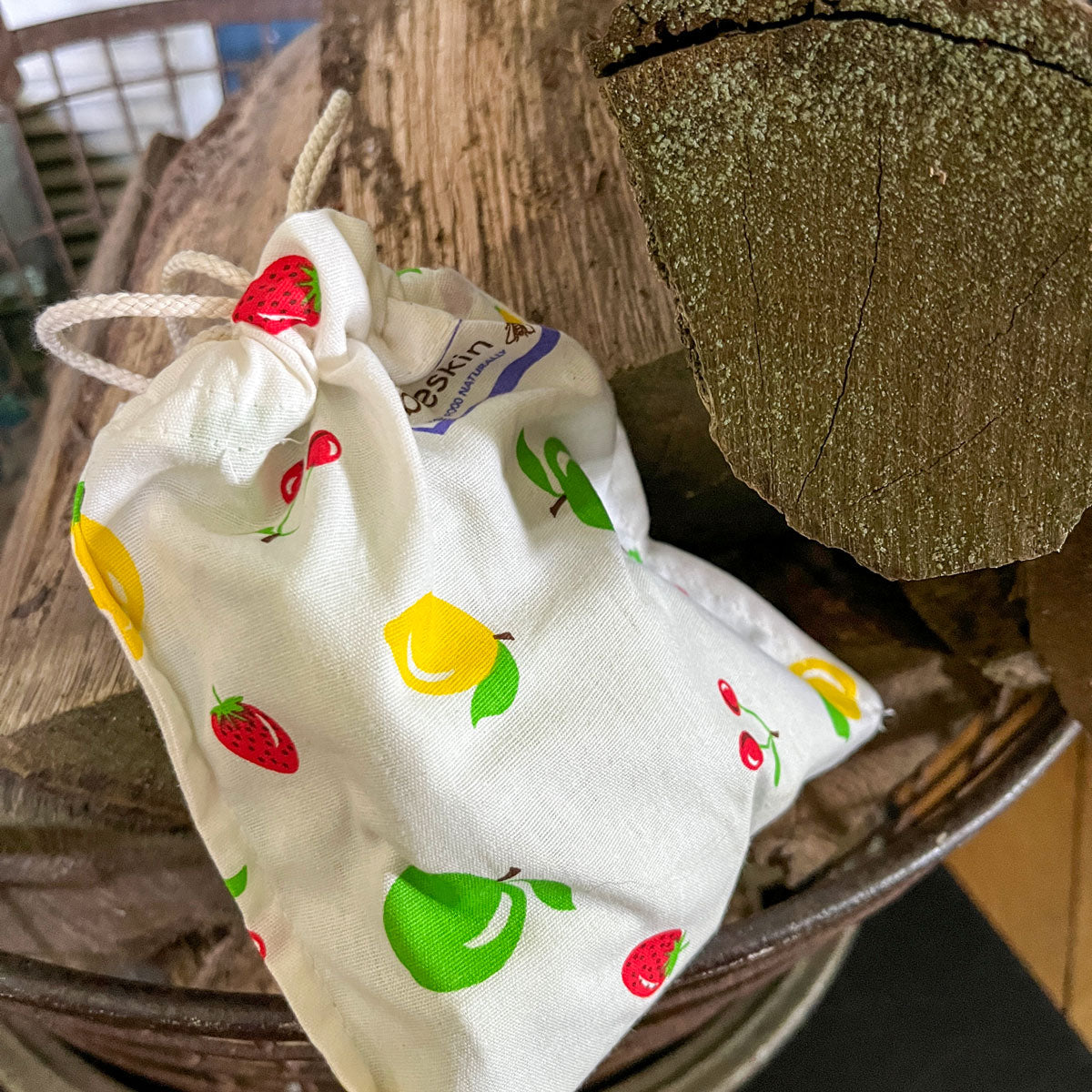 fabric bag with fruit print closed with a twine lies on firewood
