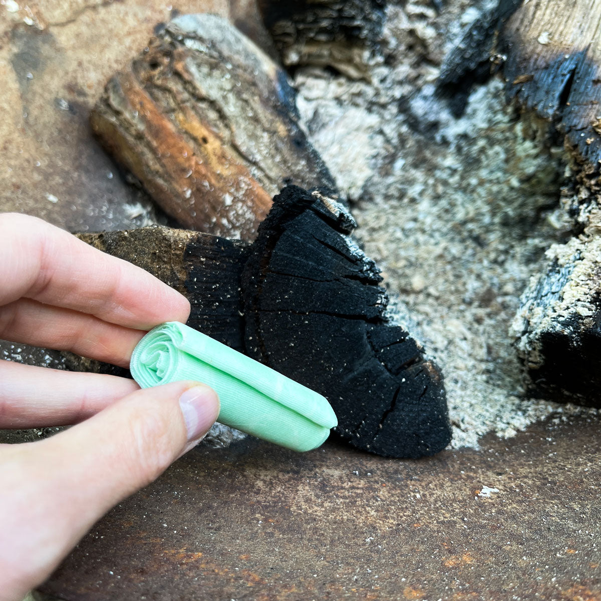 hand putting beeskin firestarter in a campfire