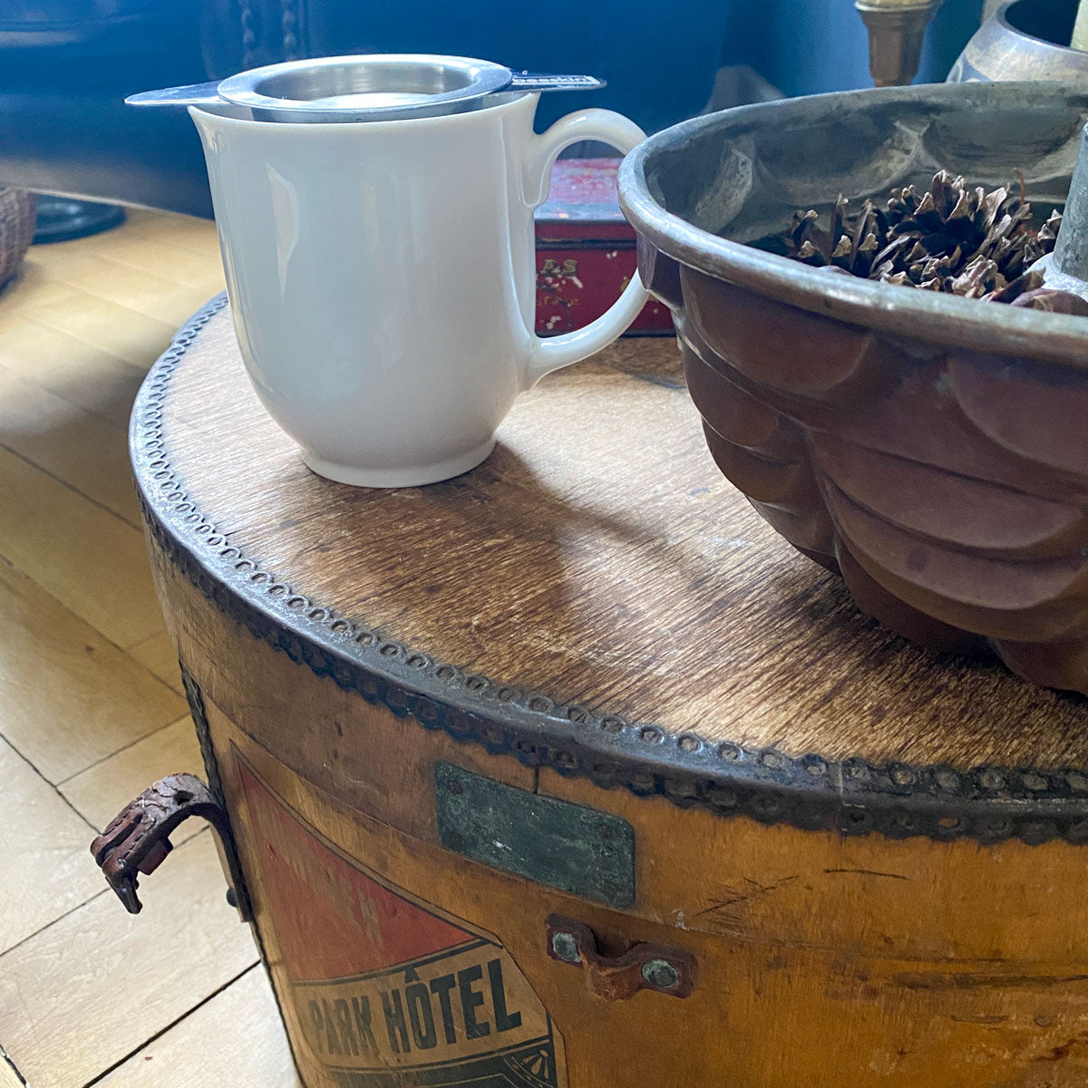 white tea cup with tea infuser filled with tea standing on a living table