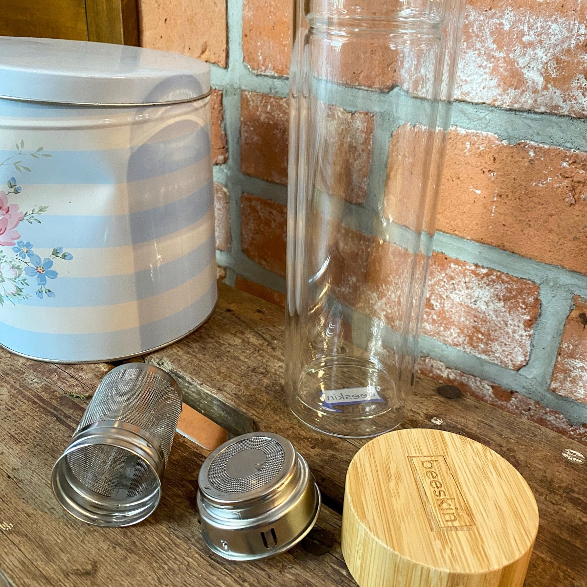 glass beeskin tea bottle standing on q wooden table in front of a wall