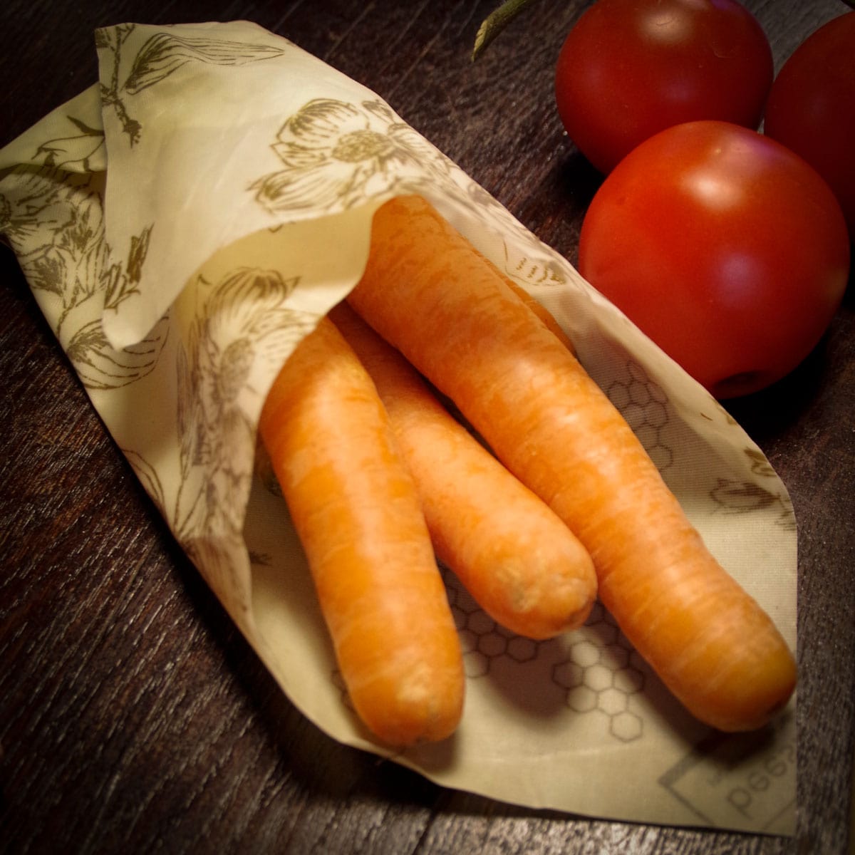 carrots wrapped in beeskin beeswax wrap flower next to tomatoes