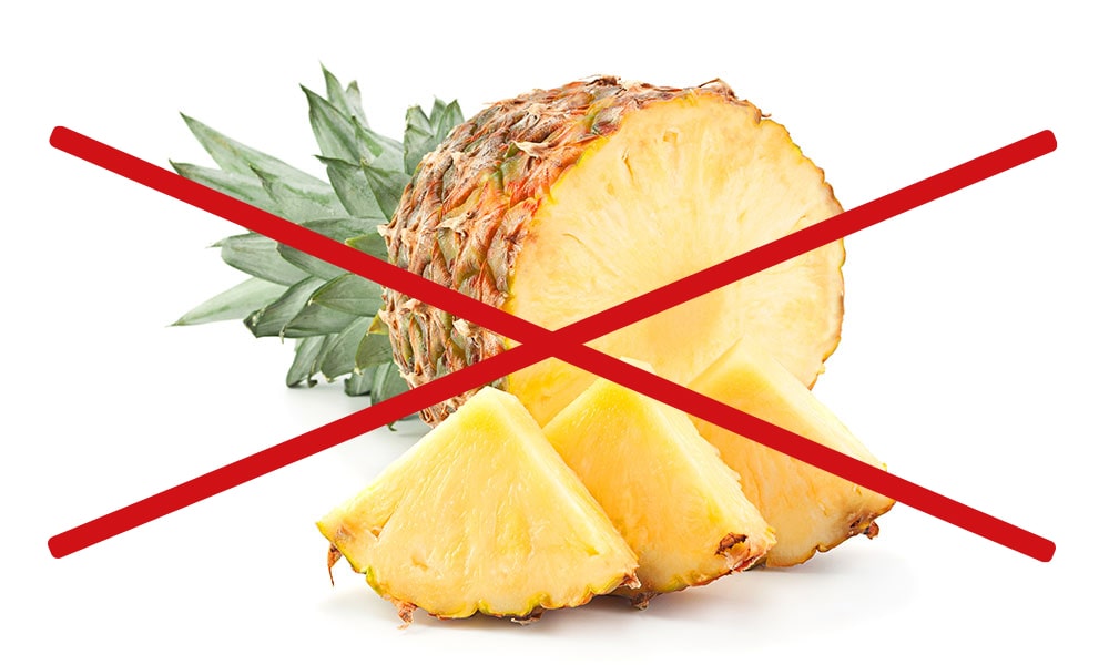 a cut pineapple with some pieces in front of it. with a Red Cross on top of the image