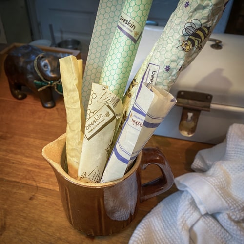 a porcelain mug with beeskin beeswax rolls in it to store them standing on a wooden table
