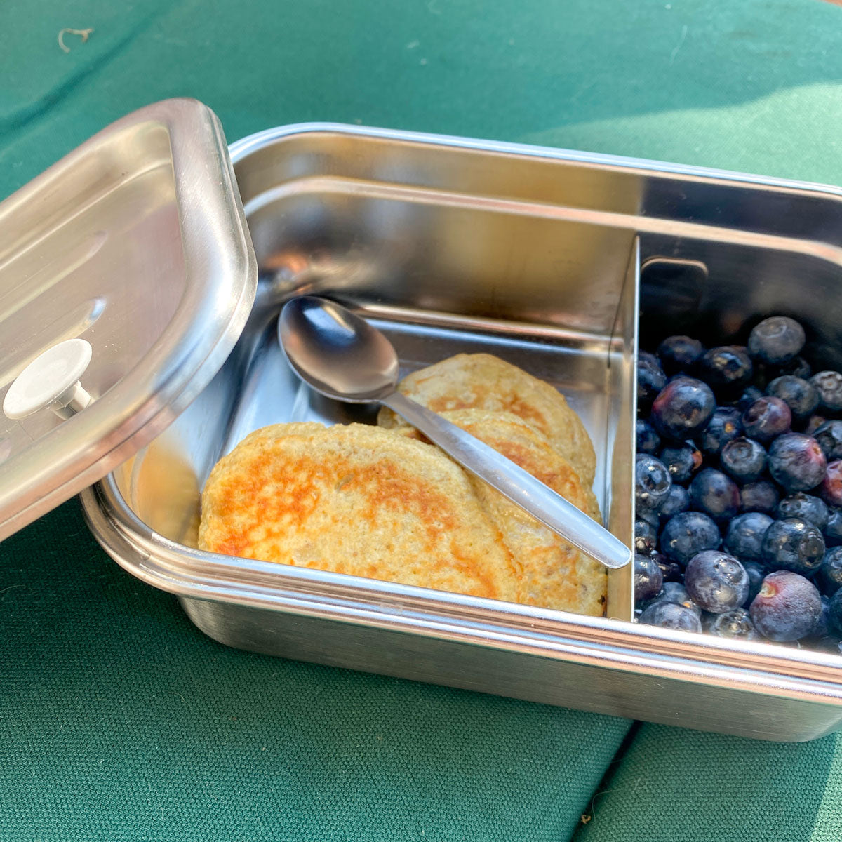 open stainless steel snack box filled with pancakes and blueberries