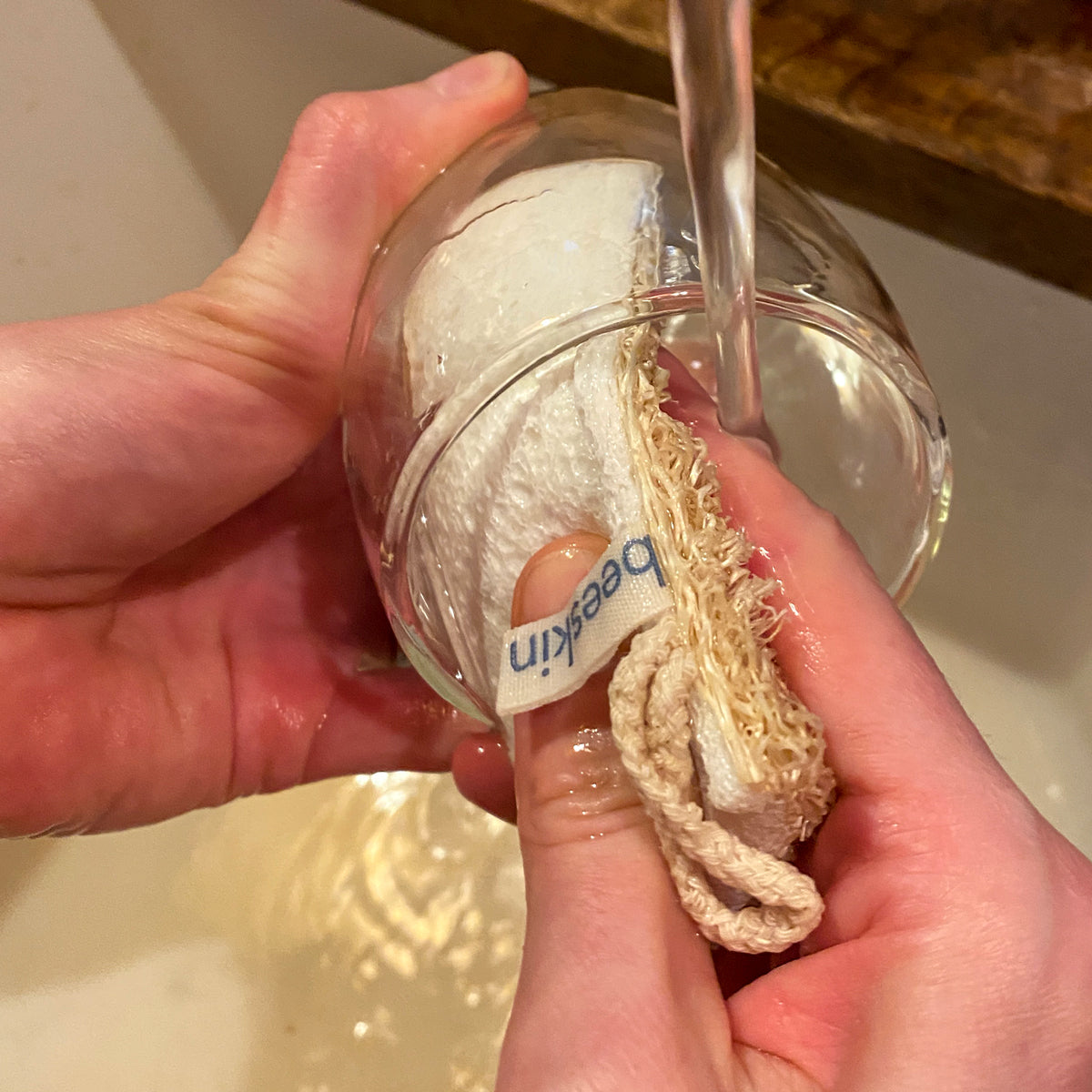 hands cleaning a glass with beeskin loofah 02 under running water