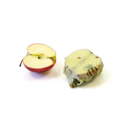 2 apple halves, one of the two halves is wrapped in beeskin in kids design